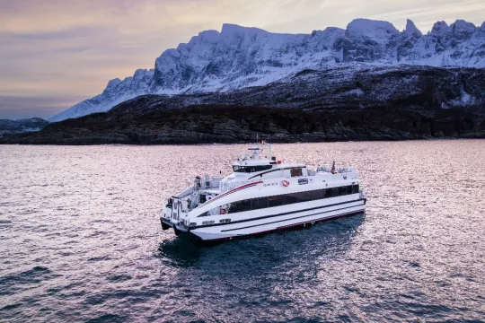 Båten i sjøen med vinterlandskap i bakgrunnen