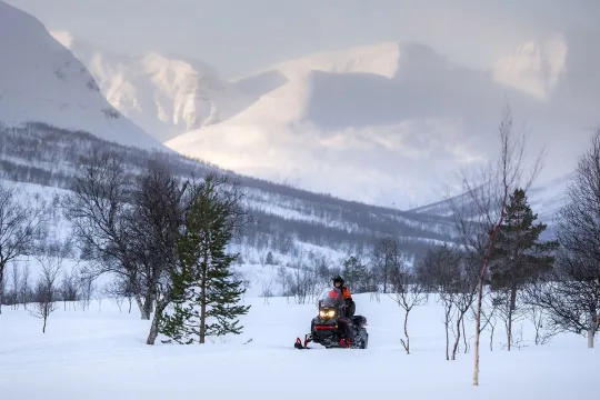 A lone snowmobile drives through the mountains