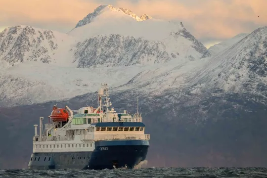 The boat at sea with high mountains in the background
