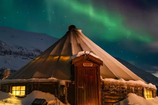 Northern Lights above a lavvu in a winter landscape