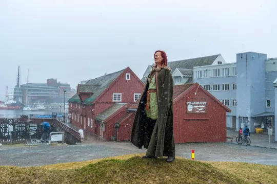 Guiden står på en haug ved siden av Polarmuseet i frakk