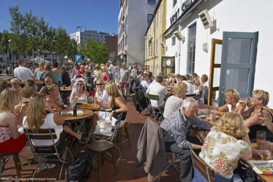 Folk nyter mat og drikke på skarven i solskinn.