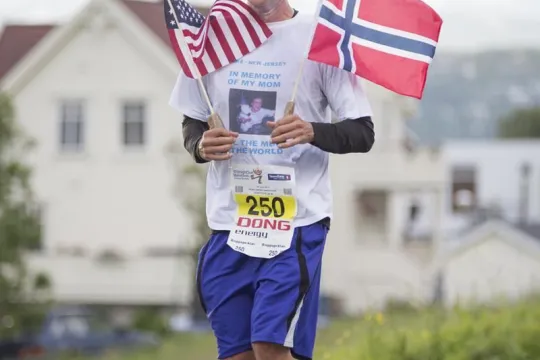 A contestant runs holding the Norwegian and American flag