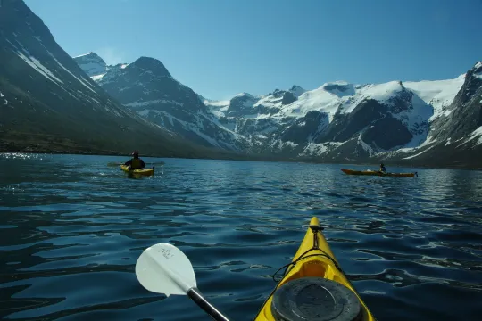 Kayak inside a fjord with tall mountain peaks around