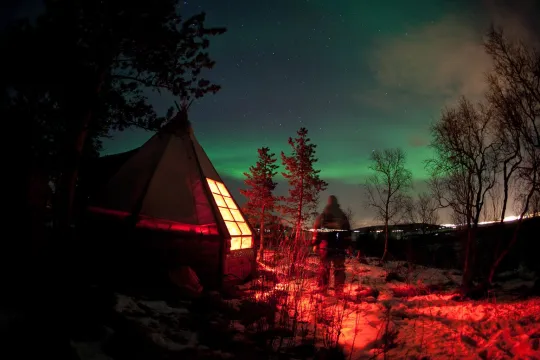 Guest outside one of the huts enjoying the northern lights in the sky