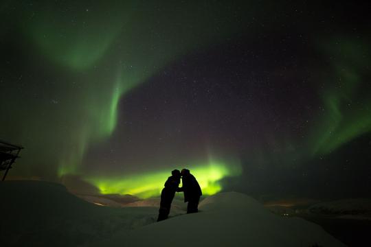 A romantic couple under the northern lights outside of Tromso