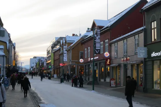 Snow-covered town street with people and shops.