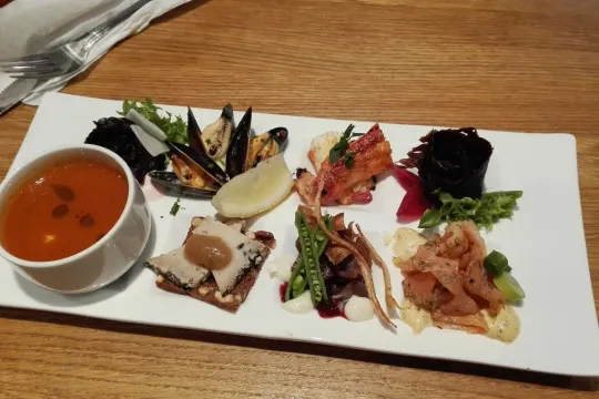 Seafood and soup starter on a white plate.
