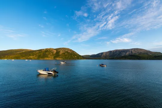 Silent ocean with boats, and mountains in the background