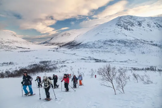 People hiking in snow-covered mountains wearing winter gear.