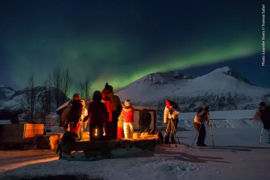 gjester på camp som ser på nordlyset som danser over fjellene
