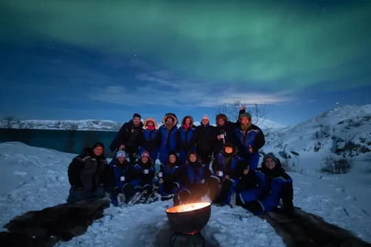 Guests sit by the fire and in front of the Northern Lights