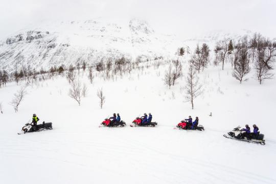 fem snøscootere kjører etter hverandre
