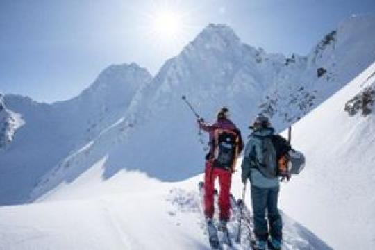 Two people skiing with mountins behind