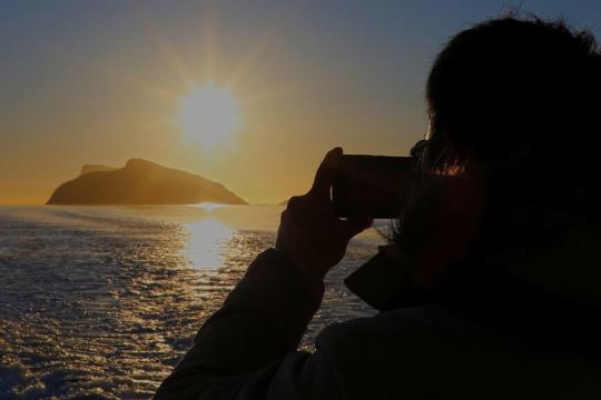 Person fotograferer midnattssola på midnattssolcruise med Explore the Arctic