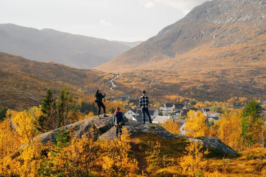 Gjester utforsker det arktiske landskapet omgitt av høstfarger og fjell.