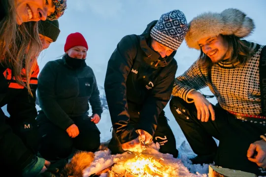 Guests lean in towards the campfire