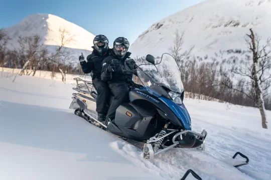 Guests pose for the camera on a snow scooter