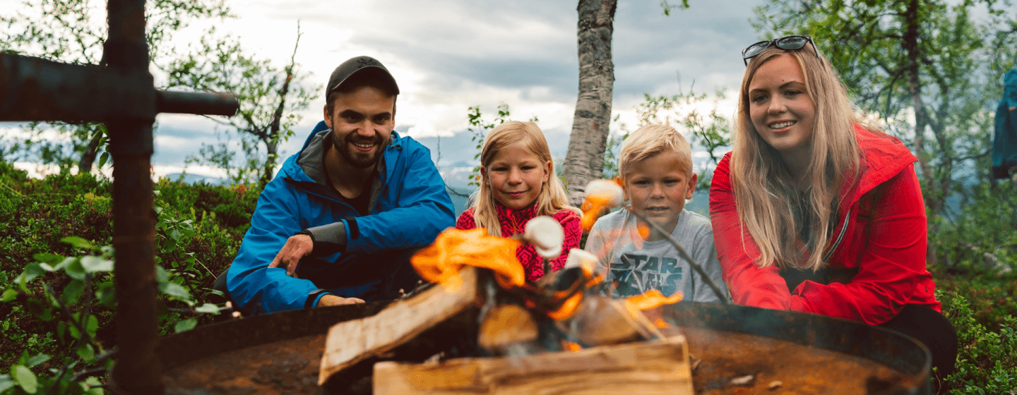 familie i skogen på piknik og steker marshmallows