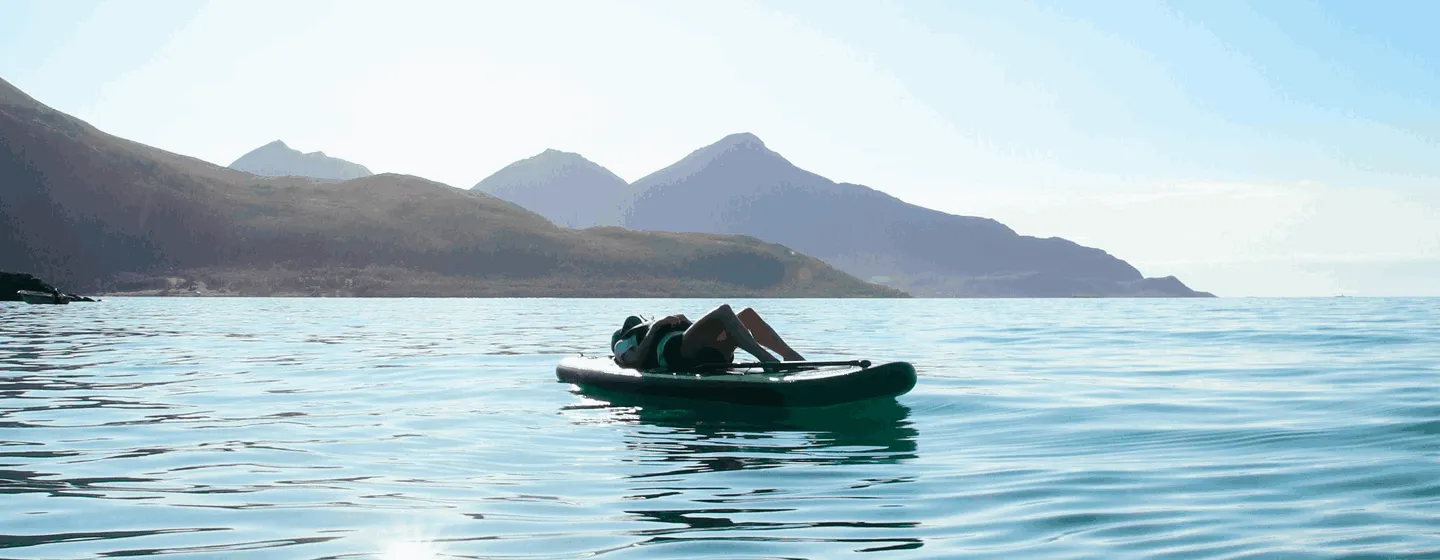 Person on paddleboard relaxing under the sun