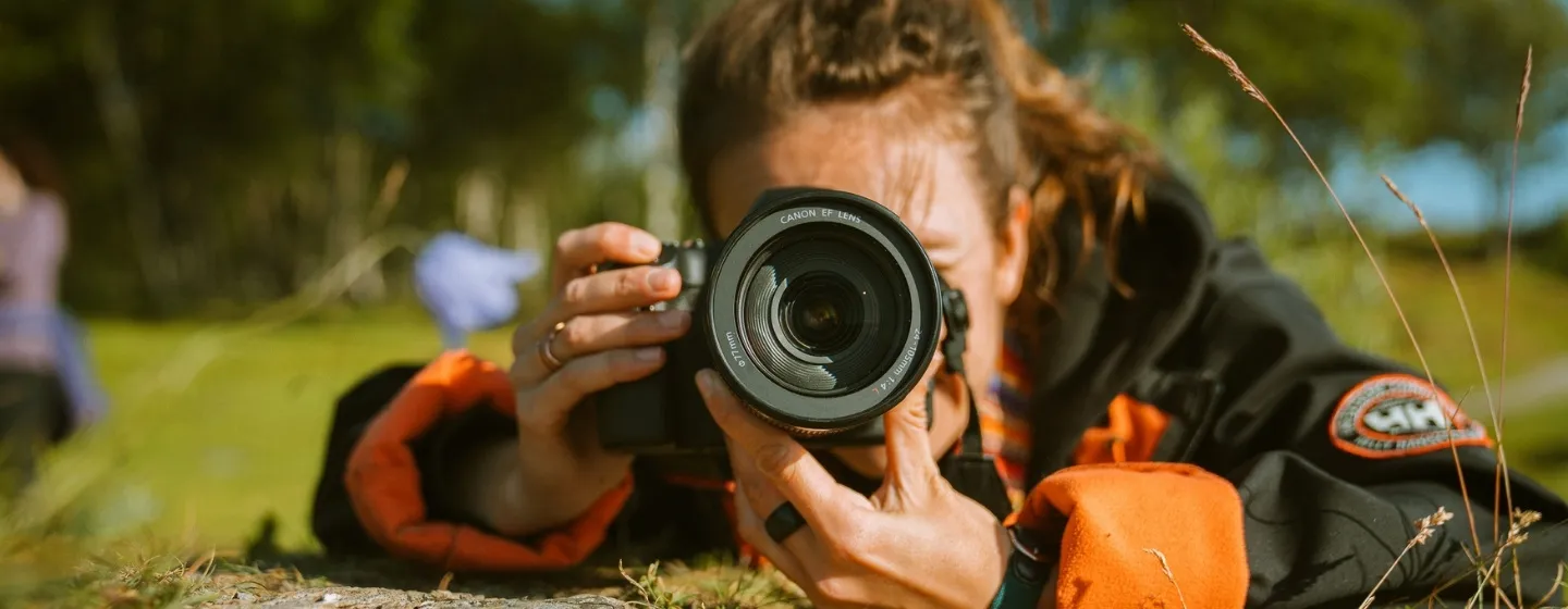 Woman laying on the ground to take a photo with a photo camera