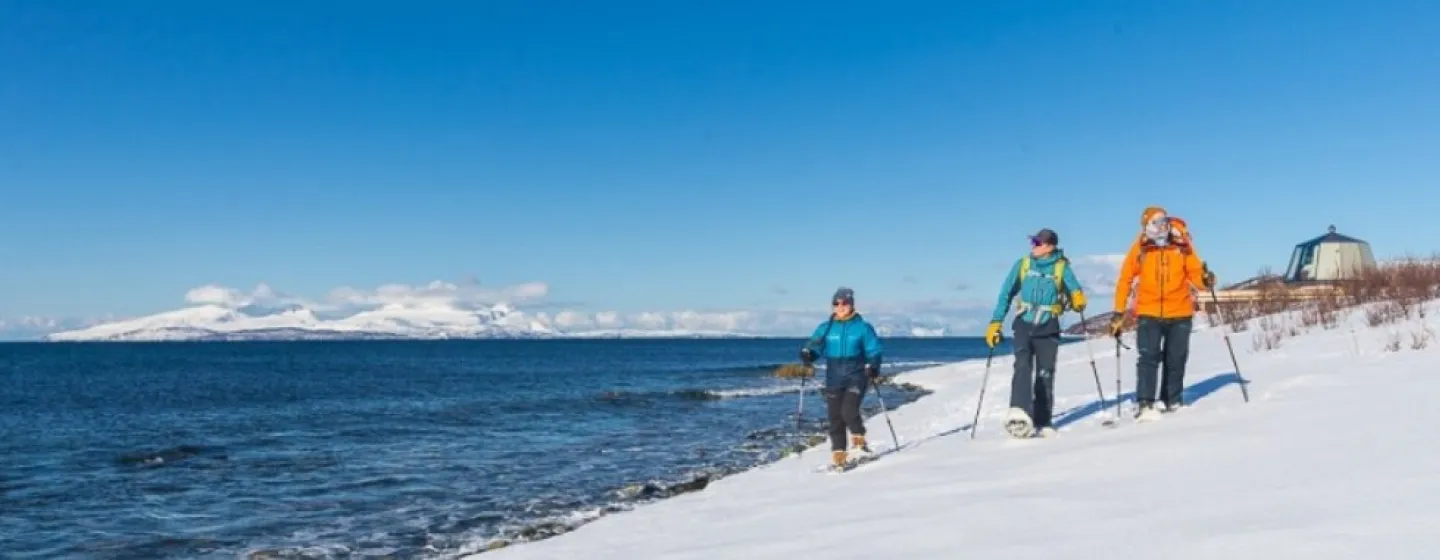 Gjester går med truger i snøen nært vannkanten