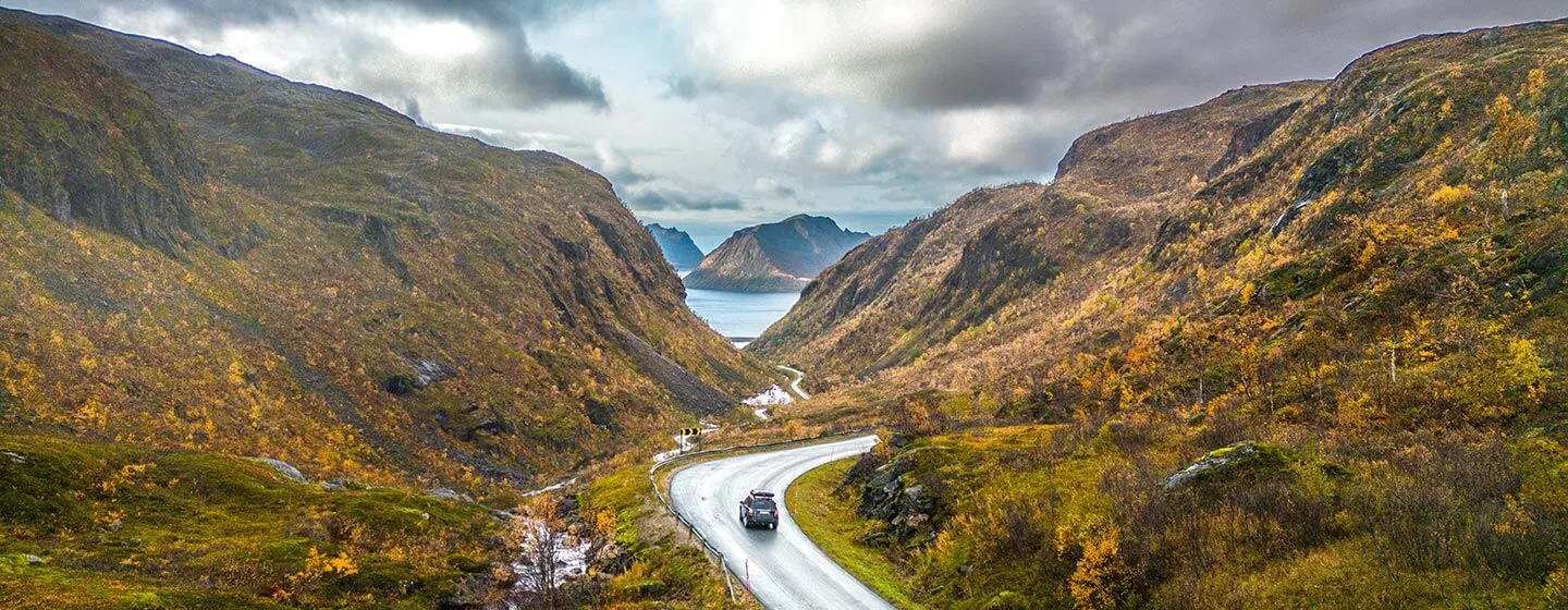 A car driving on a road through mountainous terrain in Senja