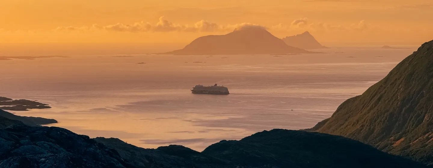 Et cruiseskip seiler under midnattssolen i Tromsø-regionen