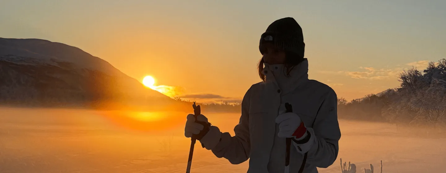 Gjest står på ski med solen i horisonten