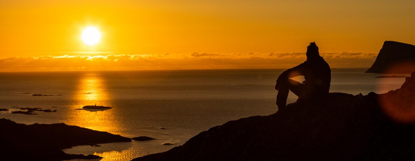 man watching the sunset over the sea during the midday sun
