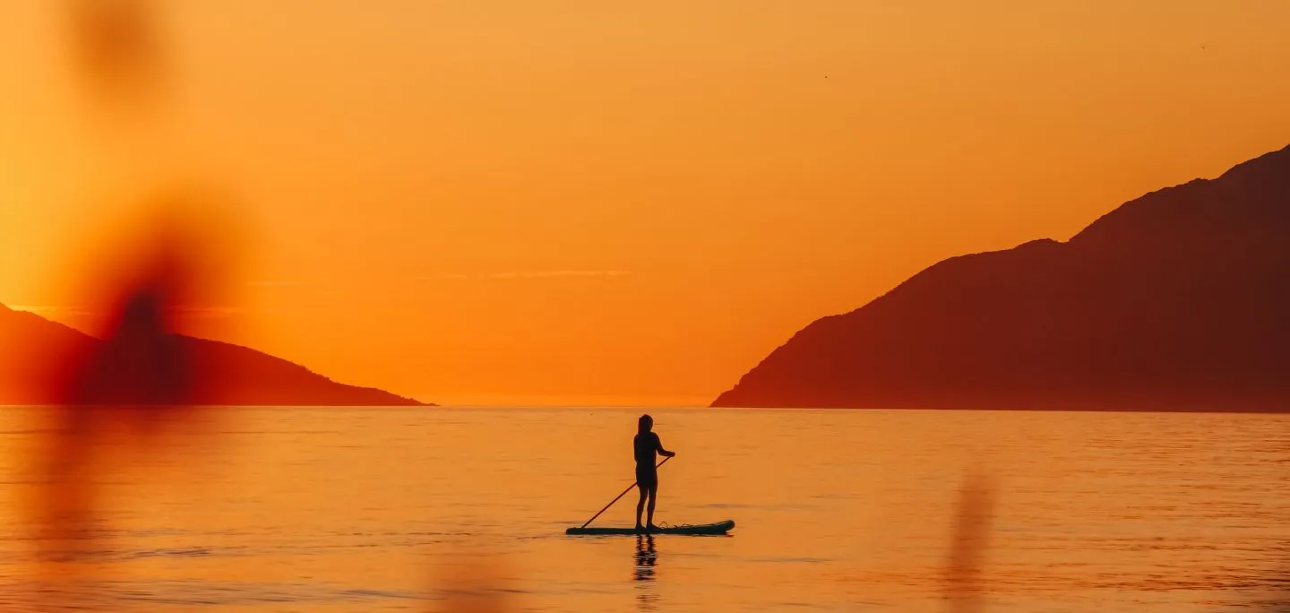 Person paddling on a SUP-board in midnight sun in the Tromso region